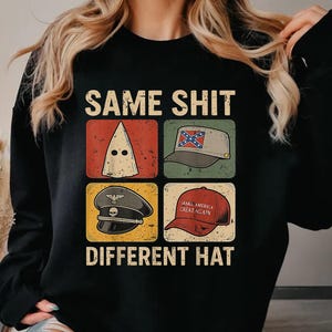 May include: Black sweatshirt with the text "SAME SHIT DIFFERENT HAT" and four images of hats. The hats include a white hood, a Confederate flag hat, a military hat, and a "Make America Great Again" hat.