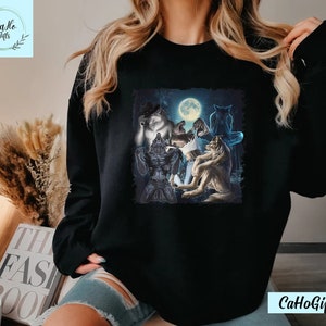 May include: Black sweatshirt with a graphic print of a group of wolves howling at the moon. The wolves are depicted in a dark forest setting with a full moon in the background.