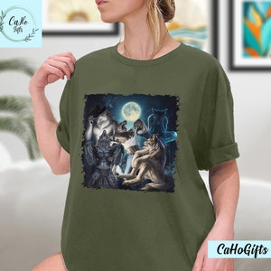 May include: A green t-shirt with a graphic print of a group of wolves howling at the moon. The wolves are in a dark forest setting.
