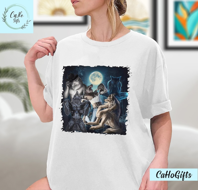 May include: A white t-shirt with a graphic print of a group of wolves howling at the moon. The wolves are depicted in a dark, shadowy setting with a full moon in the background.
