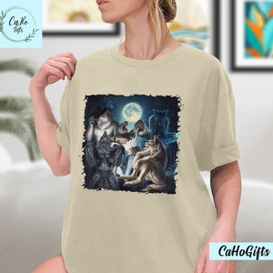 May include: A beige t-shirt with a graphic print of a group of wolves howling at the moon. The wolves are depicted in a dark, shadowy forest setting.