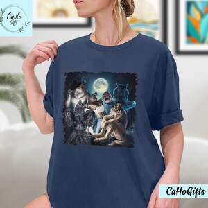 May include: A navy blue t-shirt with a graphic of a group of werewolves howling at the moon. The werewolves are depicted in a dark forest setting.