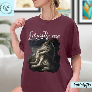 May include: A maroon t-shirt with a white wolf illustration and the text "literally me" printed on the front.
