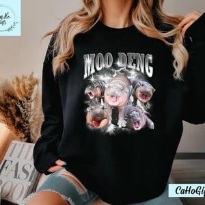 K&ouml;nnte beinhalten: Schwarzer Pullover mit einem Aufdruck von Flusspferden und dem Text "Moo Deng".