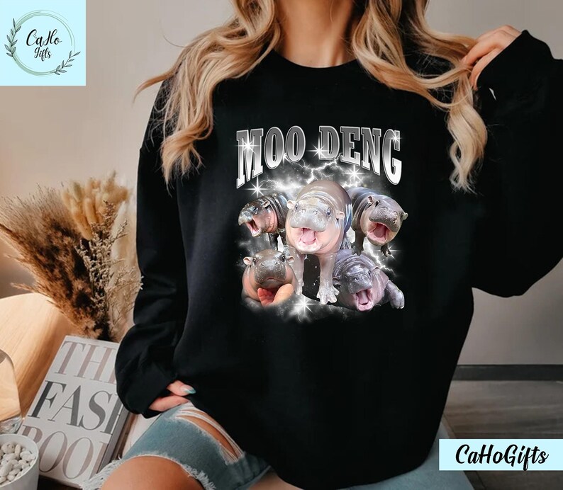 K&ouml;nnte beinhalten: Schwarzer Pullover mit einem Aufdruck von Flusspferden und dem Text "Moo Deng".