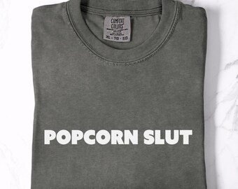 Camiseta gráfica divertida de "Popcorn Slut", unisex, negra, con memes atrevidos para cinéfilos, de algodón suave y colores cómodos.