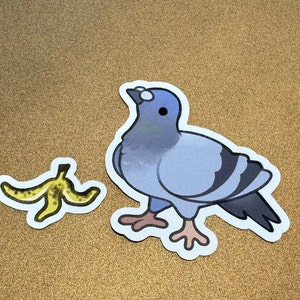 May include: A blue and gray pigeon sticker with white eyes and a yellow banana peel sticker.