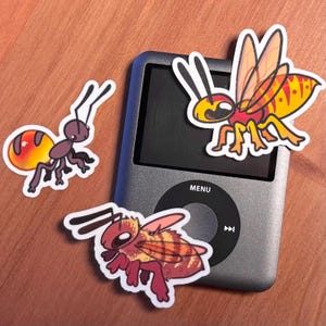 Peut inclure: Trois autocollants d'insectes colorés sur un iPod argenté. Les autocollants représentent une guêpe jaune et noire, une fourmi rouge et orange et une abeille rouge et orange.