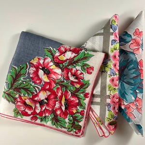 May include: Four vintage handkerchiefs with floral designs. One is blue with red poppies, another has pink and green flowers, and a third features a gray plaid pattern. The fourth handkerchief has pink and teal flowers.