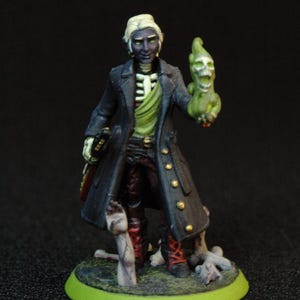 May include: Miniature figure of a skeletal character in a long black coat with gold buttons, holding a green skull. The figure has pale skin, white hair, and is standing on a green base. The figure is wearing a green shirt and red pants.