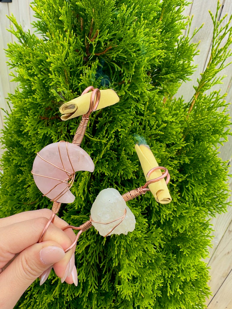 Op de afbeelding: Een set van drie keramische mokken met een gespikkelde, cr&egrave;mekleurige glazuur. Elke mok heeft een ander handgeschilderd ontwerp: een blauw en groen blad, een gele bloem en een rode bes. De mokken hebben een eenvoudig, modern ontwerp.