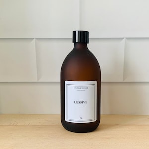 Peut inclure: Une bouteille en verre brun avec un bouchon noir et une étiquette blanche qui dit "NATUREL & DURABLE" et "LESSIVE".