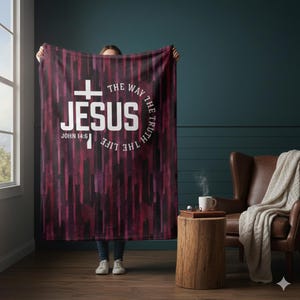 May include: A burgundy and black blanket featuring the word "JESUS" in white, a cross, and the text "THE WAY THE TRUTH THE LIFE" in a circular arrangement. The blanket also includes the text "JOHN 14:6".