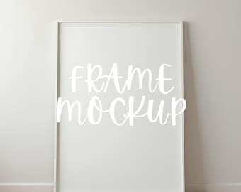 May include: White frame mockup on a white wall with a wood floor. The text "FRAME MOCKUP" is written in white on the frame.