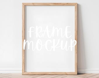 May include: A simple wooden frame mockup with a white background and the text "FRAME MOCKUP" written in white cursive font.