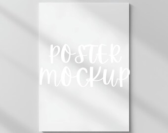 May include: A white poster mockup with the text "POSTER MOCKUP" in white cursive lettering.