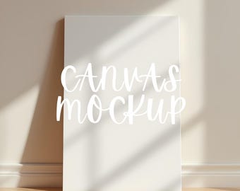Könnte beinhalten: Ein weißes Leinwand-Mockup, das an einer Wand lehnt. Die Worte "CANVAS MOCKUP" sind in einer kursiven Schriftart über die Leinwand geschrieben. Die Szene wird von natürlichem Licht beleuchtet, wodurch Schatten an Wand und Boden entstehen.