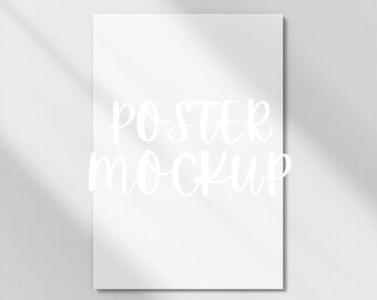 May include: A white poster mockup with the text "POSTER MOCKUP" written in white cursive font.