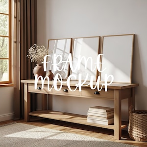 以下が含まれることがあります： 3つの額縁アートモックアップが置かれた木製のコンソールテーブル。テーブルには黒いノブが付いた3つの引き出しと下の棚があります。ドライフラワーの花瓶と本がテーブルの上にあります。「FRAME MOCKUP」というテキストが画像に重ねられています。