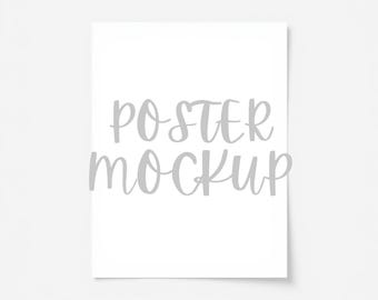 May include: A white poster mockup featuring the text "POSTER MOCKUP" in a light grey, handwritten font. The poster is centrally positioned against a white backdrop.
