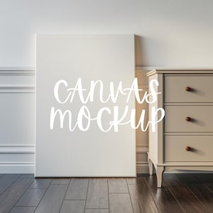 May include: A white canvas mockup leaning against a light brown dresser with three drawers. The canvas has the text "CANVAS MOCKUP" written on it in white.