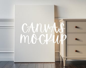 Könnte beinhalten: Ein weißer Leinwand-Mockup, der an einer hellbraunen Kommode mit drei Schubladen lehnt. Die Leinwand trägt den Text "CANVAS MOCKUP" in weiß.