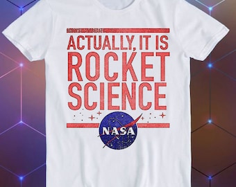 May include: White t-shirt with red text that reads "Actually, it is Rocket Science" and a blue NASA logo with stars.