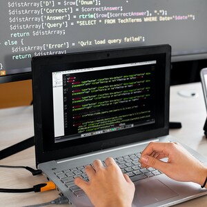 May include: A person is working on a laptop computer with a second monitor displaying code. The code on the laptop screen includes the text "placement" and "tooltip".
