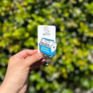 May include: A silver badge reel with a blue and white enamel pin featuring a milk carton with the text "Don't hate me just because I'm a Little Cooler".