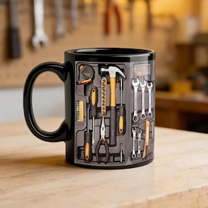 May include: Black ceramic mug with a toolbox design. The graphic shows a tape measure, hammer, screwdrivers, pliers, and wrenches. The mug has a black handle and a glossy finish. Ideal for a handyman or DIY enthusiast, it's a practical and stylish gift.