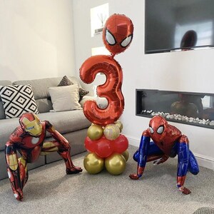 Puede incluir: Decoraciones de globos rojos y azules para una fiesta de cumplea&ntilde;os. Los globos tienen forma de n&uacute;mero 3, Spiderman y Iron Man.