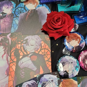 Puede incluir: Una colección de botones y tarjetas de personajes de anime con varios personajes con diferentes colores de cabello y ropa. Los botones son redondos y tienen un acabado brillante e iridiscente. Las tarjetas son rectangulares y tienen un acabado brillante. Una rosa roja está en el centro de la imagen.