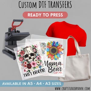 May include: Image showing a heat press, red t-shirt, tote bag, and DTF transfer sheets with skull and floral, and sunflower designs. Text reads "CUSTOM DTF TRANSFERS READY TO PRESS" and "AVAILABLE IN A5 • A4 • A3 SIZES".