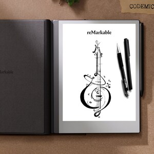 Puede incluir: Tableta reMarkable en blanco y negro con una cubierta negra. La pantalla muestra un dise&ntilde;o de instrumento musical y la palabra "reMarkable". Dos bol&iacute;grafos negros est&aacute;n colocados a la derecha de la tableta.