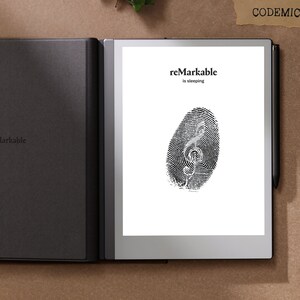 Puede incluir: Una tableta reMarkable negra con una huella dactilar en la pantalla. El texto "reMarkable is sleeping" se muestra. Un l&aacute;piz &oacute;ptico negro est&aacute; a la derecha de la tableta. La tableta est&aacute; en una funda negra. La palabra "CODEMIC" est&aacute; arriba a la derecha.