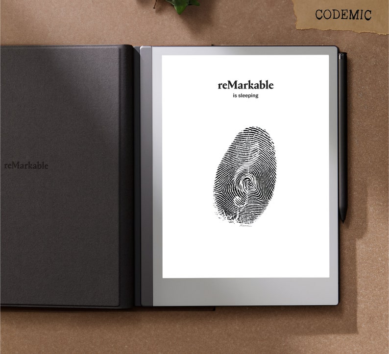 Puede incluir: Una tableta reMarkable negra con una huella dactilar en la pantalla. El texto "reMarkable is sleeping" se muestra. Un l&aacute;piz &oacute;ptico negro est&aacute; a la derecha de la tableta. La tableta est&aacute; en una funda negra. La palabra "CODEMIC" est&aacute; arriba a la derecha.