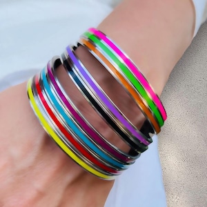May include: A stack of colorful bangles with a silver base and a single bright colored stripe around each bangle.