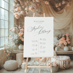May include: A white wedding welcome sign with black calligraphy script that reads "Welcome to the wedding of Sophie & Anthony". The sign lists the wedding day schedule with icons and times for the welcome toast, ceremony, lunch, cocktail hour, dinner, and fireworks.