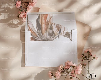 Op de afbeelding: Een witte envelop met een bloemenontwerp aan de voorkant. De envelop is omringd door roze bloemen en een lichtbruine achtergrond.
