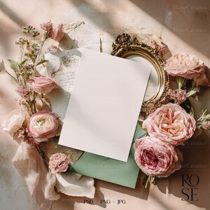 Romantic fine art wedding mockup flatlay with pink roses, vintage golden frame, green envelope and sunlight — elegant floral scene for stationery designs.