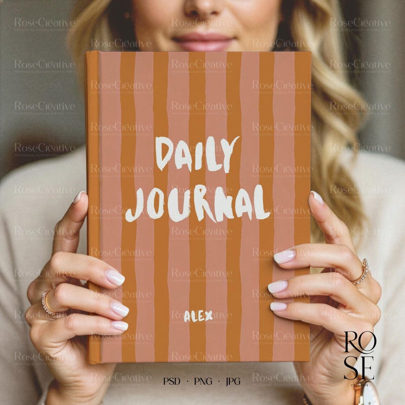A lifestyle photograph of a woman softly smiling while holding a blank, cream-colored A5 hardcover book directly in front of her. She is holding the book with both hands, showcasing a delicate rose gold watch and rings. The lighting is soft and natural, creating a feminine, high-end aesthetic.