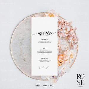 May include: A white wedding menu card with a black calligraphy font for the word "menu". The menu includes a starter, main course, and dessert. The card is on a plate with dried flowers.