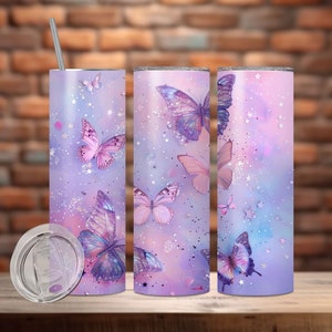 Peut inclure: Ensemble de trois gobelets en acier inoxydable avec un fond dégradé violet et rose et un motif de papillons. Les gobelets ont un couvercle transparent et une paille.