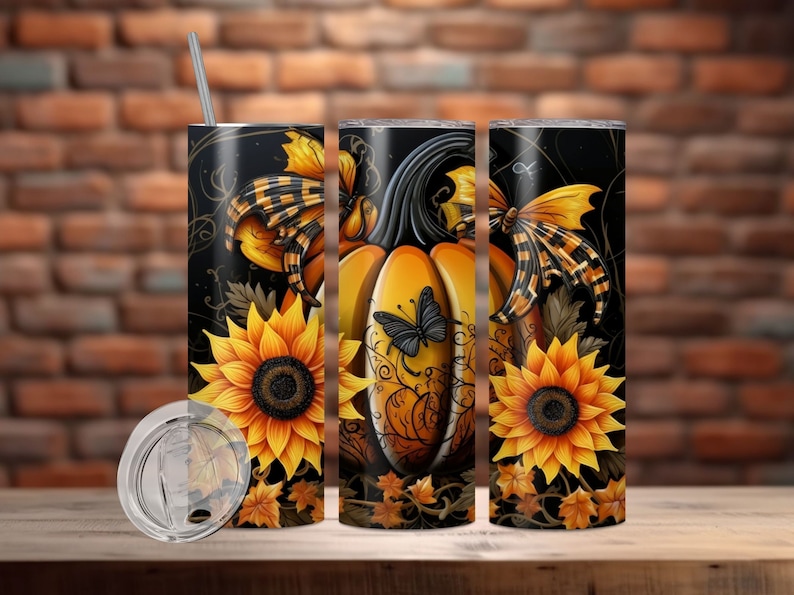 May include: A stainless steel tumbler with a fall-themed design. The design features a large orange pumpkin, sunflowers, and butterflies against a black background. The tumbler includes a lid and a straw.