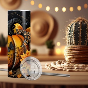 May include: A stainless steel tumbler with a pumpkin and butterfly design. The tumbler features a black background with orange pumpkins, yellow sunflowers, and butterflies. A clear lid and a silver straw are included.