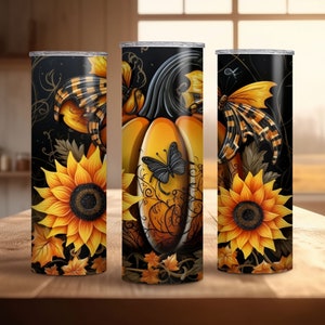 May include: Three tall, cylindrical tumblers with a fall theme. Each tumbler features a sunflower, a pumpkin, and a butterfly design in shades of orange, yellow, and black. The background is black with decorative swirls.