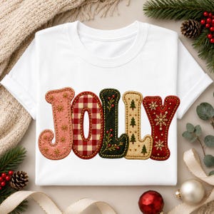 Può includere: Una t-shirt bianca a maniche corte con la parola JOLLY stampata in grandi lettere stilizzate. Ogni lettera ha una trama unica: rosa con stelle dorate, quadretti rossi e bianchi, verde scuro con bacche, beige con alberelli e rosso con fiocchi di neve.