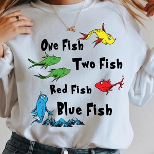 May include: White sweatshirt with a graphic of fish and the text "One Fish Two Fish Red Fish Blue Fish".