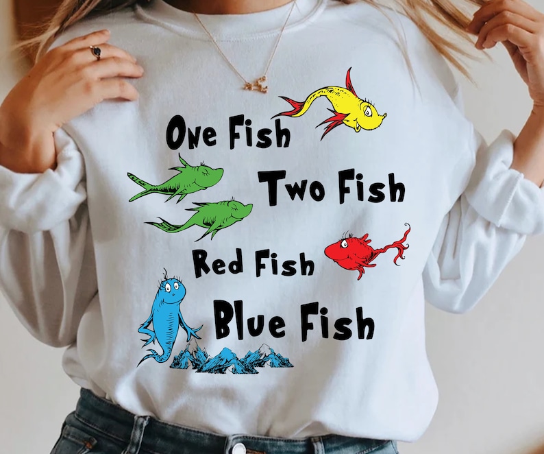 May include: White sweatshirt with a graphic of fish and the text "One Fish Two Fish Red Fish Blue Fish".