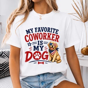 以下が含まれることがあります： 「MY FAVORITE COWORKER IS MY DOG」という文字がプリントされた白い半袖Tシャツ。星条旗柄のサングラスとバンダナを身につけたゴールデンレトリバーのイラストと、足跡や骨のアイコンがデザインされています。